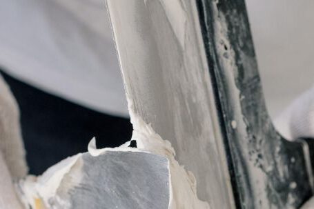 DIY Projects - Crop unrecognizable male in gloves holding putty knives while working at new home