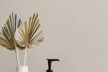 Storage Hacks - Set of cosmetic supplies near decorative leaves in vase on marble shelf