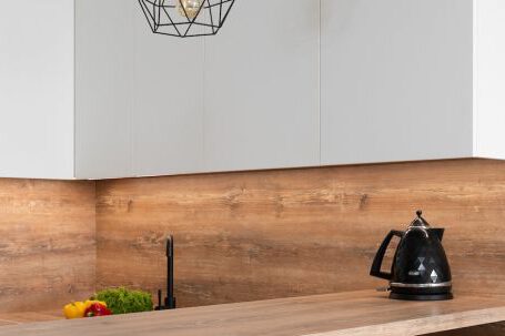 Kitchen Renovation - Interior of modern white kitchen with timber table and metal geometrical glowing lamps
