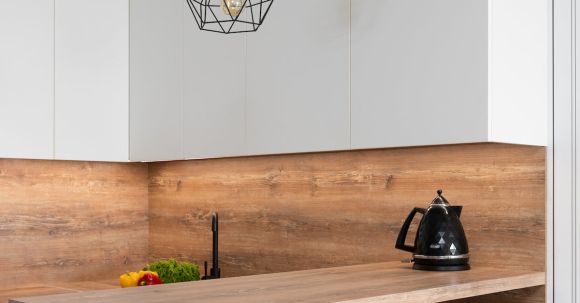 Kitchen Renovation - Interior of modern white kitchen with timber table and metal geometrical glowing lamps