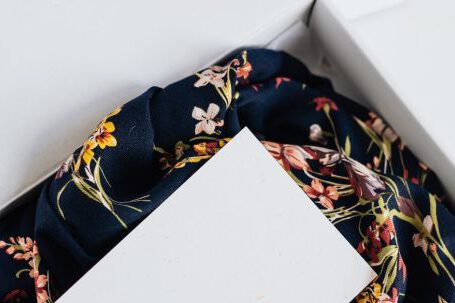 Storage Solutions - From above of stylish black silk floral pattern cloth with white visit card mockup placed in white carton box after receiving postal delivery of online order