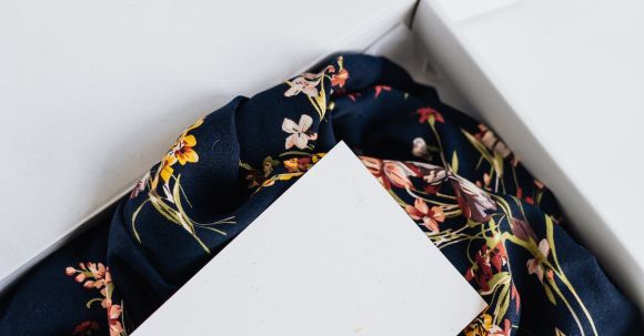 Storage Solutions - From above of stylish black silk floral pattern cloth with white visit card mockup placed in white carton box after receiving postal delivery of online order