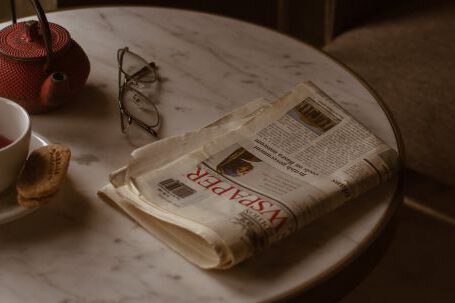 Retro Home - From above of round marble textured table with tea set placed near newspaper and eyeglasses in retro style cafe