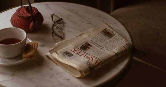 Retro Home - From above of round marble textured table with tea set placed near newspaper and eyeglasses in retro style cafe