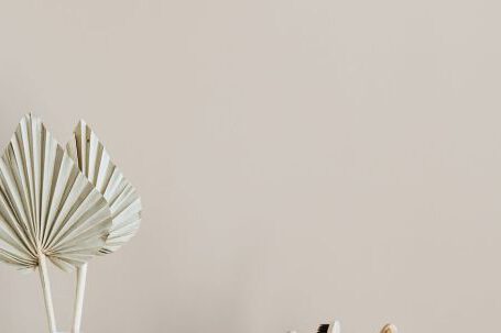 Sustainable Decor - White creative vase with decorative artificial plants and organic soap with body brush placed near set of bamboo toothbrushes in ceramic holder and dark glass reusable bottle of lotion
