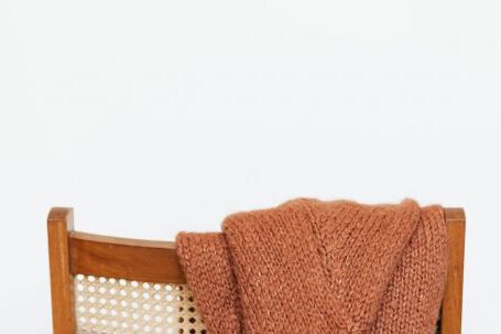 Storage Hacks - Brown coarse wool sweater hung on back of woooden chair against white wall
