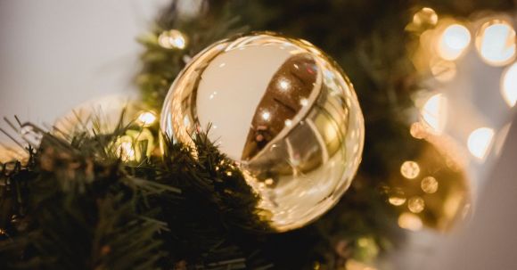 Seasonal Decor - Christmas golden bauble on artificial fir garland full of lights on blurred background